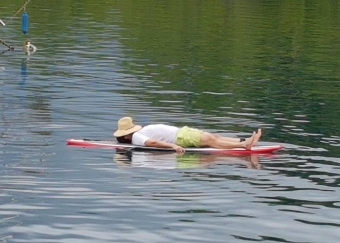 A man on Fiji time relaxes on a surfboard.